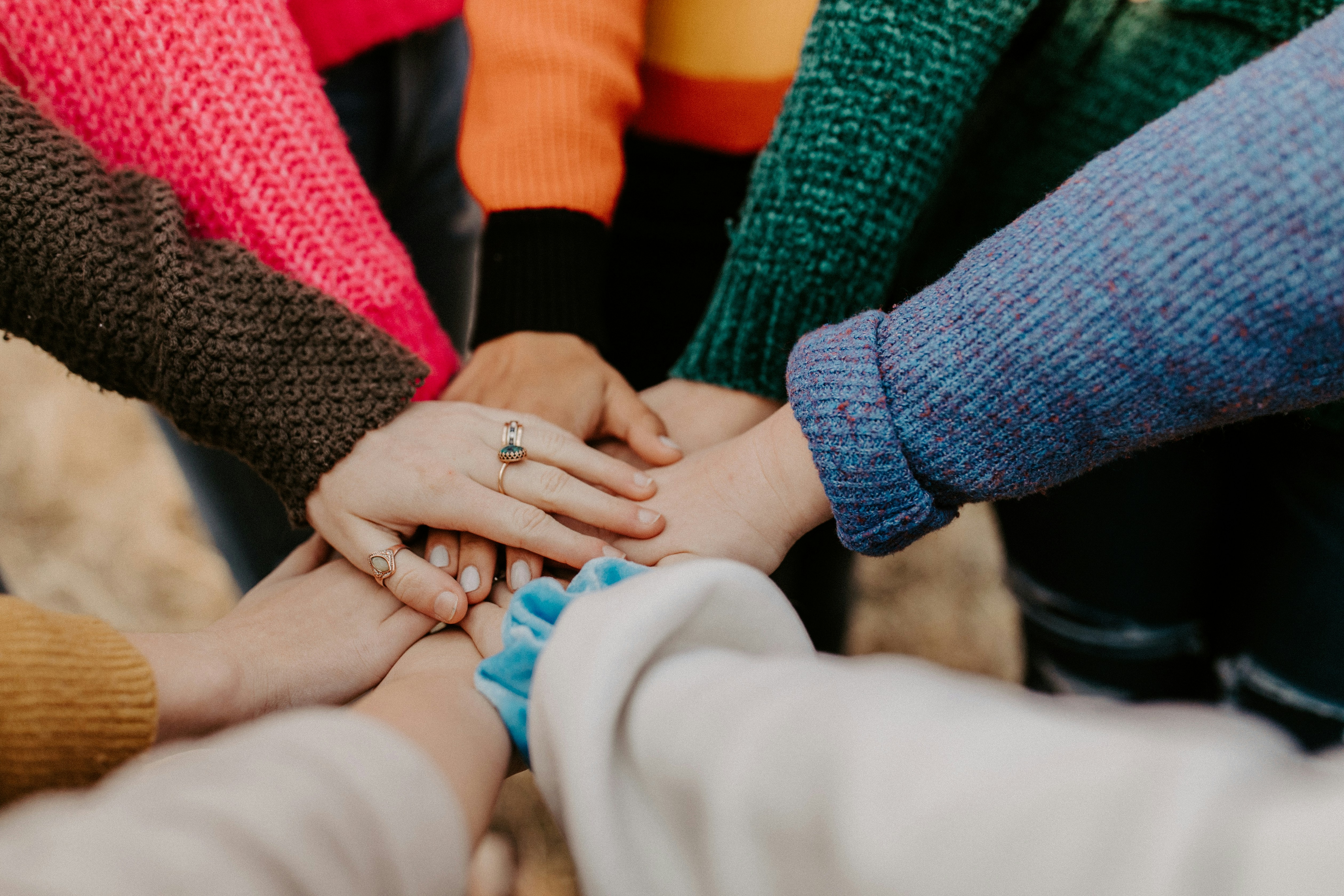 hannah-busing-Zyx1bK9mqmA-unsplash Community group holding hands symbolizing connection and support