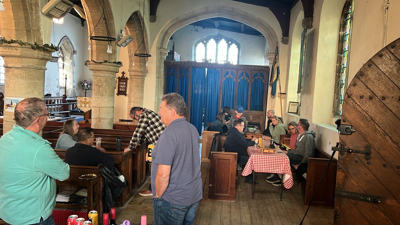 People sitting at tables in the Church Hall enjoying conversation while playing boardgames